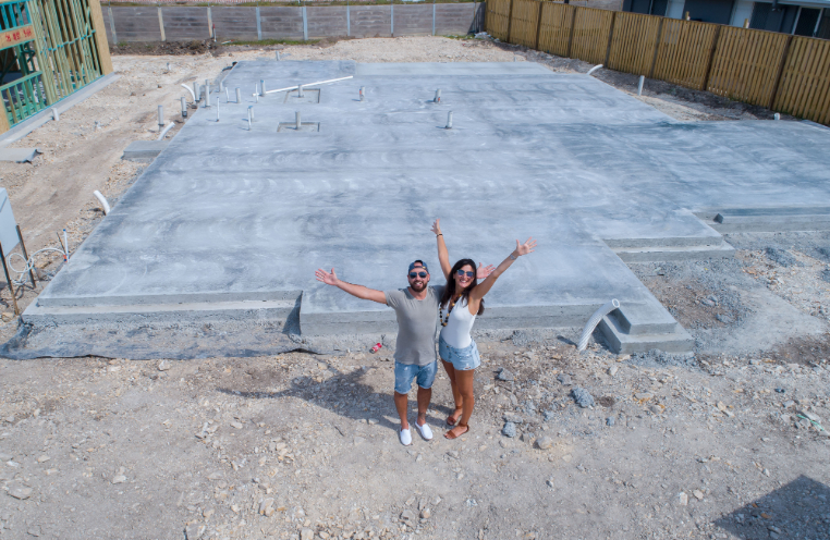 Happy couple standing in front of home foundation
